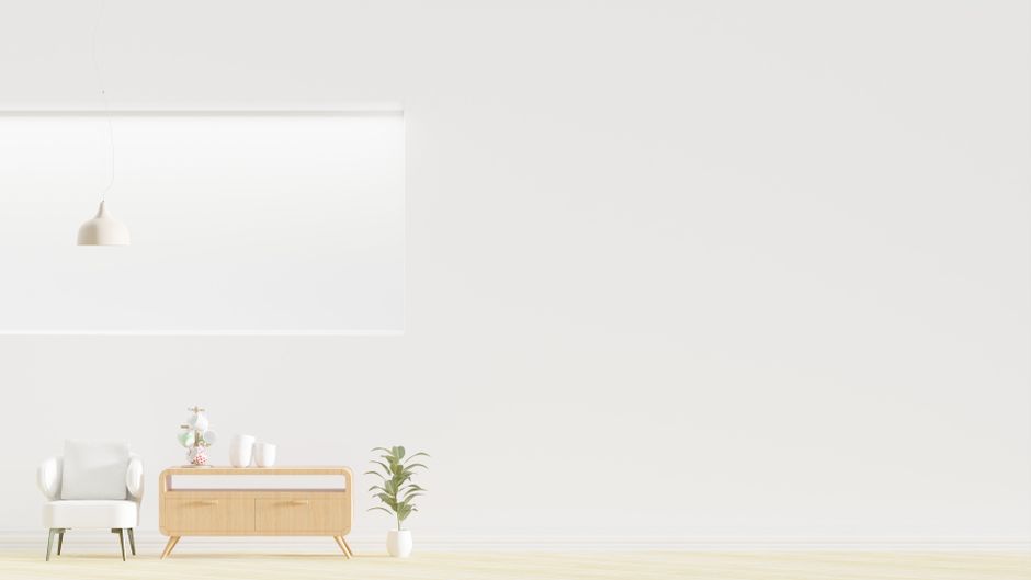 Bright minimalist room featuring an armchair, wooden dresser, and greenery.